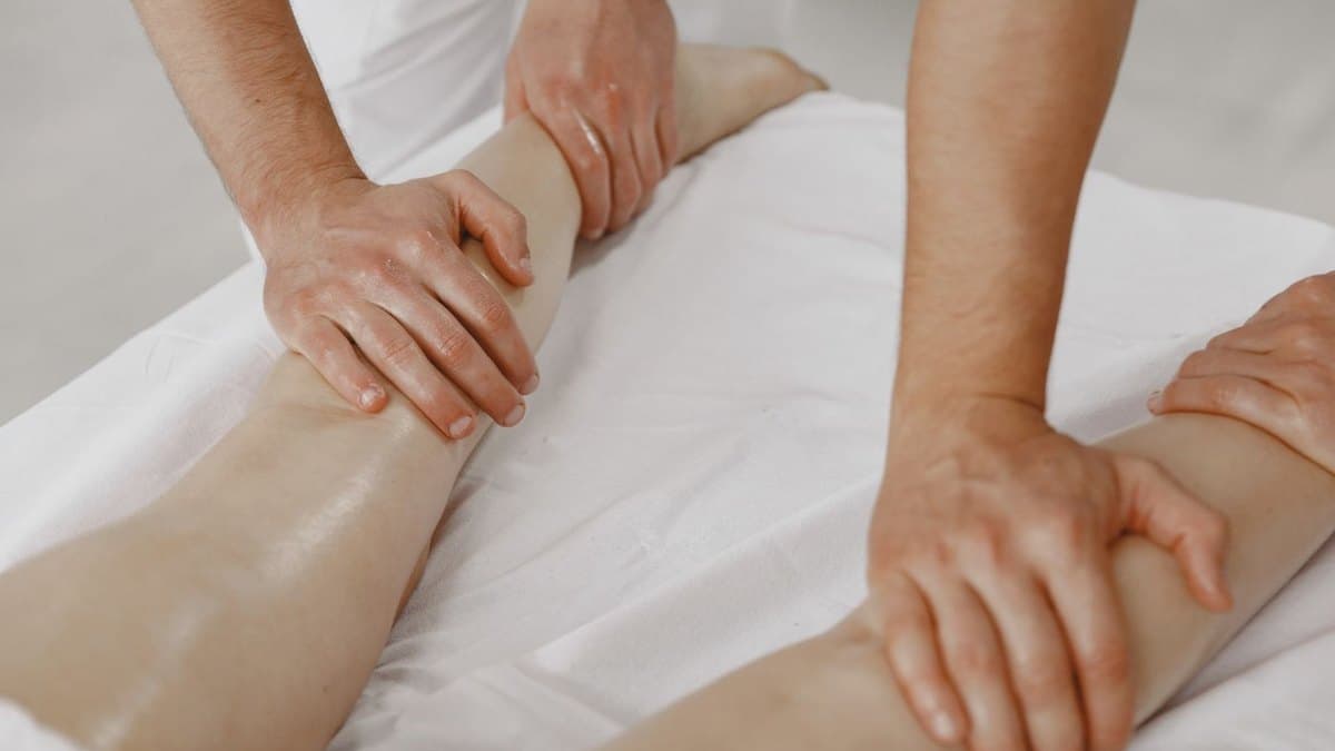Mains posées à plat sur une jambe, drap blanc, pendant un drainage lymphatique